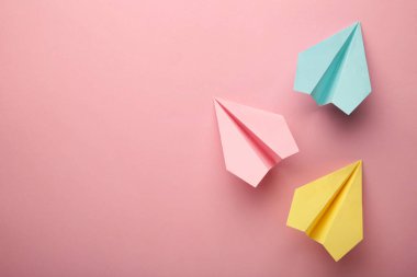 Pembe arka planda renkli kağıt uçak, iş yarışması konsepti. Üst görünüm