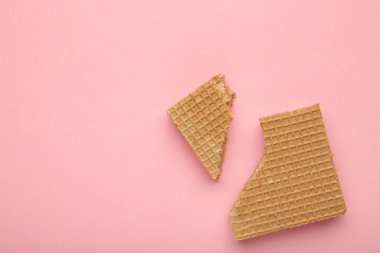 Kare çikolatalı wafe bisküvisi pembe arka planda kırılmış. Üst görünüm.