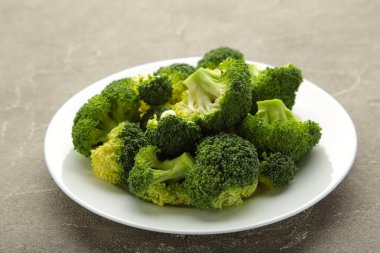 Bir kase pişmiş yeşil brokoli, gri arka planda. Üst görünüm.