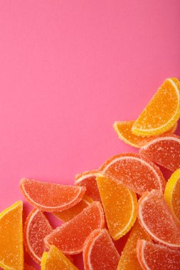 Limon şeklinde tatlı marmelat ve pembe arka planda portakal dilimleri. Dikey fotoğraf. Üst görünüm