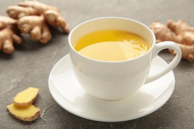 Gri arka planda beyaz bardakta limonlu zencefil çayı. Üst görünüm