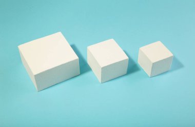 Mavi arka planda beyaz kare podyumlar. Kozmetik ürünler, ürünler, ayakkabılar, çantalar, saatler için moda gösterisi. Üst görünüm