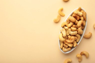 Bej arka planda beyaz tabakta kaju fıstığı..