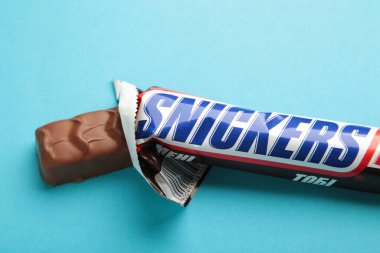 Nikolaev, Ukrayna - 19 Aralık 2021 Snickers çikolatası mavi arka planda. Snickers, Amerikan markası Mars tarafından üretilen bir çikolatadır. Üst görünüm.
