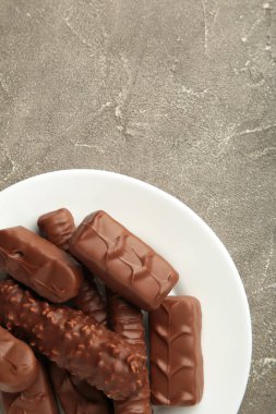 Gri arka planda beyaz tabakta çikolata karışımı. Dikey fotoğraf