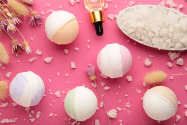 Aroma banyo bombaları, kuru çiçekli spa kompozisyonu ve pembe arka planda tuz. Üst görünüm