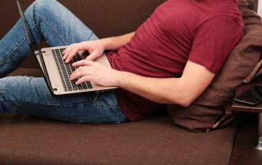 Kanepede dizüstü bilgisayarla çalışan bir iş adamı. Üst görünüm