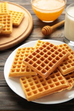 Kahverengi arka planda Belçika waffle 'ı. Ballı ve sütlü Belçika waffle 'ı. Taze pişmiş Belçika waffle 'ı..