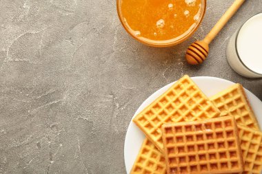 Gri arka planda Belçika waffle 'ı. Ballı ve sütlü Belçika waffle 'ı. Taze pişmiş Belçika waffle 'ı..