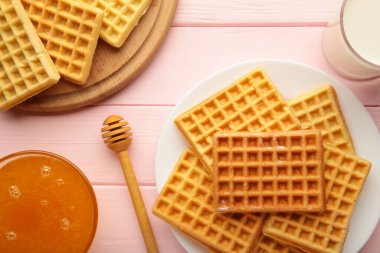 Pembe arka planda Belçika waffle 'ı. Ballı ve sütlü Belçika waffle 'ı. Taze pişmiş Belçika waffle 'ı..