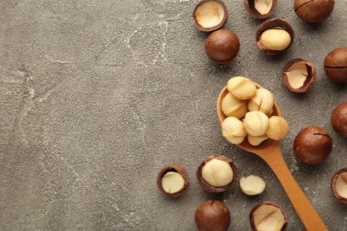 Gri arka planda tahta kaşıkta Macadamia fındıkları.