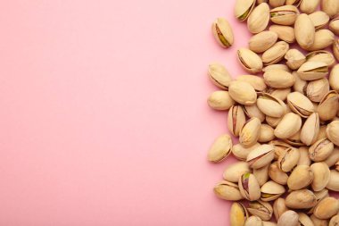 Pembe arka planda fotokopi alanı olan Pistachios yığını. Üst görünüm.
