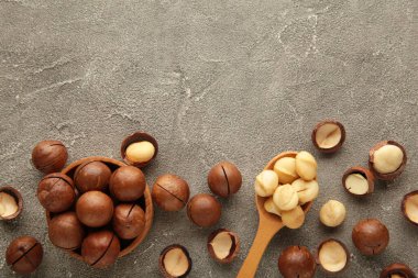 Gri arka planda tahta kaşıkta Macadamia fındıkları.