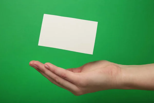 Hand Med Flygande Visitkort Grön Bakgrund Ovanifrån — Stockfoto