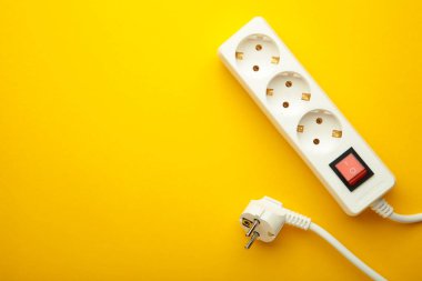 Sarı arkaplanda elektrikli beyaz taşınabilir soket