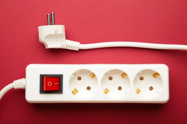 Kırmızı arkaplanda elektrik beyaz taşınabilir soket