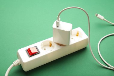 Yeşil arka planda bağlı aygıt ile elektrik beyaz portatif soket. Üst görünüm.