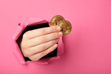 Pembe kâğıdı delen Bitcoin 'li kadın eli. Üst görünüm