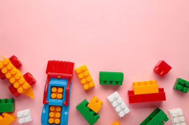 Çocukların yapıcısının çok renkli blokları pembe arka planda yatıyor.