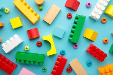 Çocukların inşaatçısının çok renkli blokları mavi arka planda yatıyor. Üst görünüm