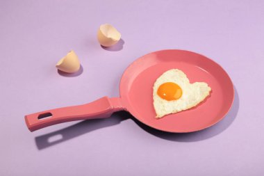 Pembe tavalı ve kalbi beyaz ve pembe arka planda olan yaratıcı bir fikir. En az yemek ve aşk konsepti. Sevgililer Günü için kahvaltı fikri ve romantik bir sabah. Üst görünüm