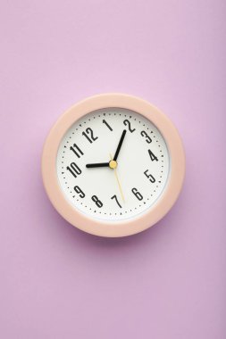 Mor arka planda pembe saat. Dikey fotoğraf