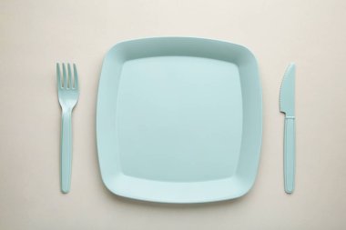Gri arka planda mavi plastik tek kullanımlık sofra takımı. Üst görünüm