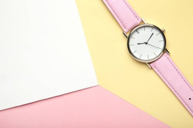 Pastel arka planda pembe kayışlı, fotokopi alanı olan bir kol saati. Üst görünüm