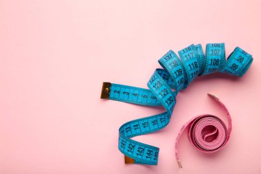 Pembe arka plan üzerinde metrik ölçekli mavi ve pembe plastik şerit. Üst Manzara. Diyet kavramı