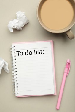 Gri arka plan, planlama ve tasarım konseptiyle ilgili bir liste hazırlamak için kahve fincanı ve defter. Dikey fotoğraf