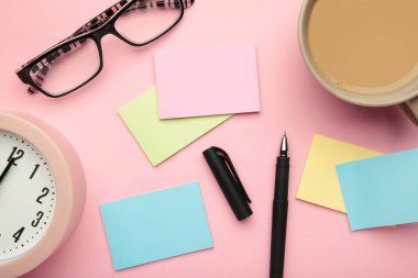 Üzerinde yapışkan notların fotoğrafı, pembe arka planda bir fincan kahve ve bardaklar. Üst görünüm