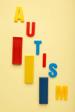 Otizm. Otizm spektrum bozukluğu. Otizm kelimesi bej arka planda oyun hamuruyla yapılmış. Üst görünüm