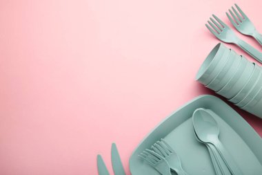 Bright plastic reusable tableware on a pink background. Top view