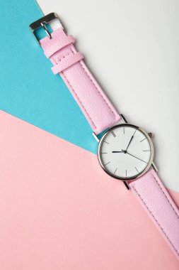 Pastel arka planda pembe kayışlı, fotokopi alanı olan bir kol saati. Üst görünüm