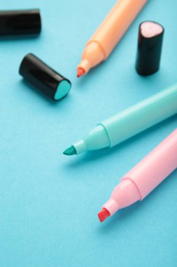 İşaretleyicileri aç ve mavi arkaplanda metin için yer aç. Pembe, mavi ve turuncu fosforlu kalemler.