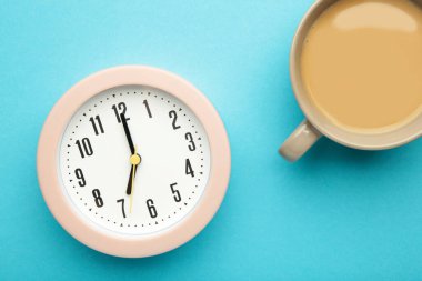 Mavi arka planda çalar saat ve bir fincan kahve. Üst görünüm