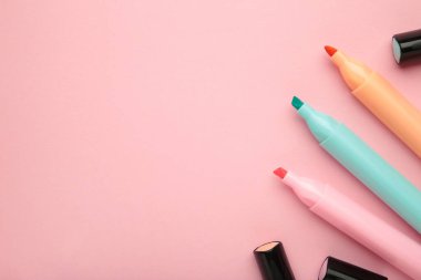 İşaretleyiciler açık ve pembe arka planda metin için boşluk var. Pembe, mavi ve turuncu fosforlu kalemler.