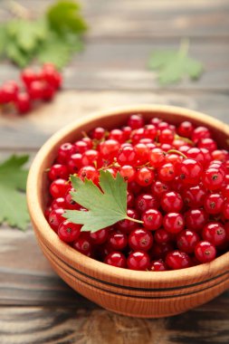 Kahverengi arka planda olgun kırmızı üzümlü kase. Üst Manzara. Dikey fotoğraf