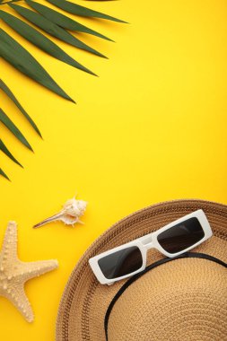 Yaz tatili yatıyordu. Palmiye yaprakları, hasır şapka ve sarı arka planda güneş gözlüğü. Uzayı kopyala Üst görünüm
