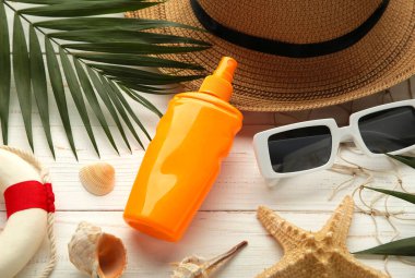 Plaj düz aksesuarları. Güneş şapkası, palmiye dalı, güneş kremi şişesi ve deniz kabukları. Yaz tatili konsepti. Üst görünüm