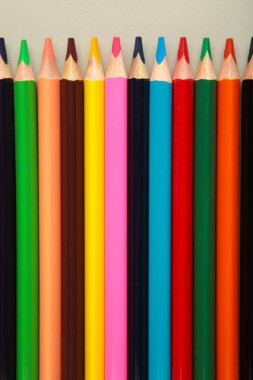 Gri kağıttaki renkli kalemlerin arka planı. Üst görünüm.