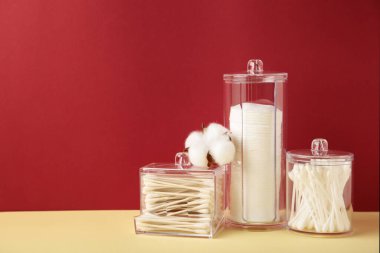 Pamuk pedler ve pamuk çubuklar konteynırlarda bej ve kırmızı arka planda pamuk çiçekleri. Üst görünüm