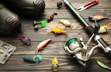 Nikolaev, Ukraine - 08 july, 2022: Fishing rods and spinnings in the composition with accessories for fishing on brown background. Top view.