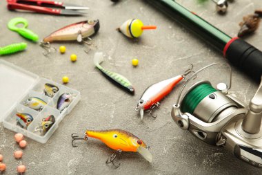 Nikolaev, Ukrayna - 08 Temmuz 2022: Gri arkaplanda balık tutmak için aksesuarlarla kompozisyonda olta ve dönme dolaplar. Üst görünüm.