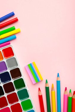 Boya, kalem ve makas. Pembe arka planda okul aksesuarları. Dikey fotoğraf.