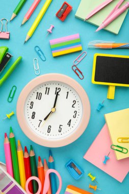 Çalar saat, boya, kalem ve makas. Mavi arka planda okul aksesuarları. Dikey fotoğraf.