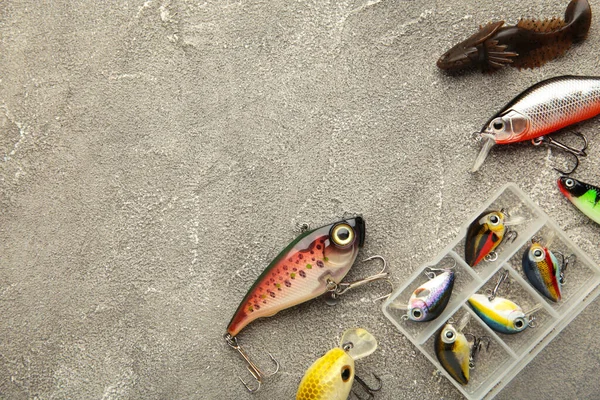 Nikolaev, Ukraine - 08 july, 2022: Colorful fishing lures, wobbler, spinner, on grey wood. Top view.