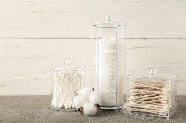 Pamuk pedler ve pamuk çubuklar gri arka planda pamuk çiçekleri olan kaplarda. Üst görünüm