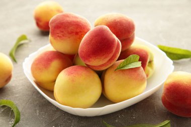 Plate of ripe peaches on grey background. Top view