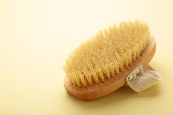 Brush for dry anti-cellulite massage or brushing on beige background. Beauty concept.